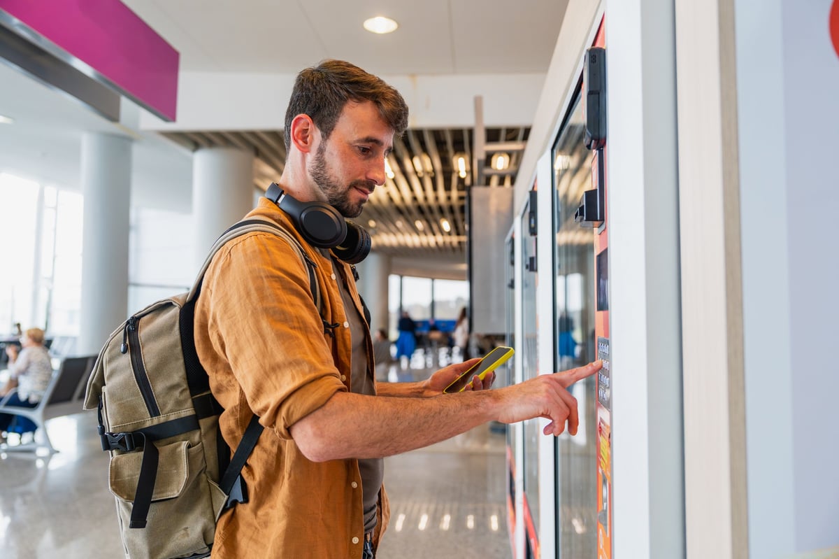 Young man using a vending machine while traveling